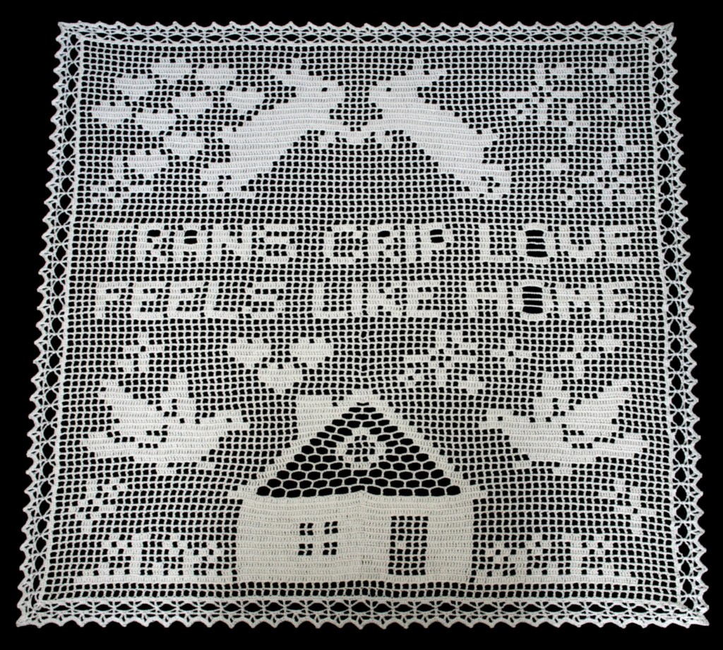 A large filet crochet banner with decorative border. In the centre of the banner are the words 'trans crip love feels like home'. Below the text is a house with hearts coming out of the chimney, doves either side of it, and a flowered garden. Above the text are two hares jumping towards each other, and more hearts from the chimney. Throughout the work are stars and sparkles.